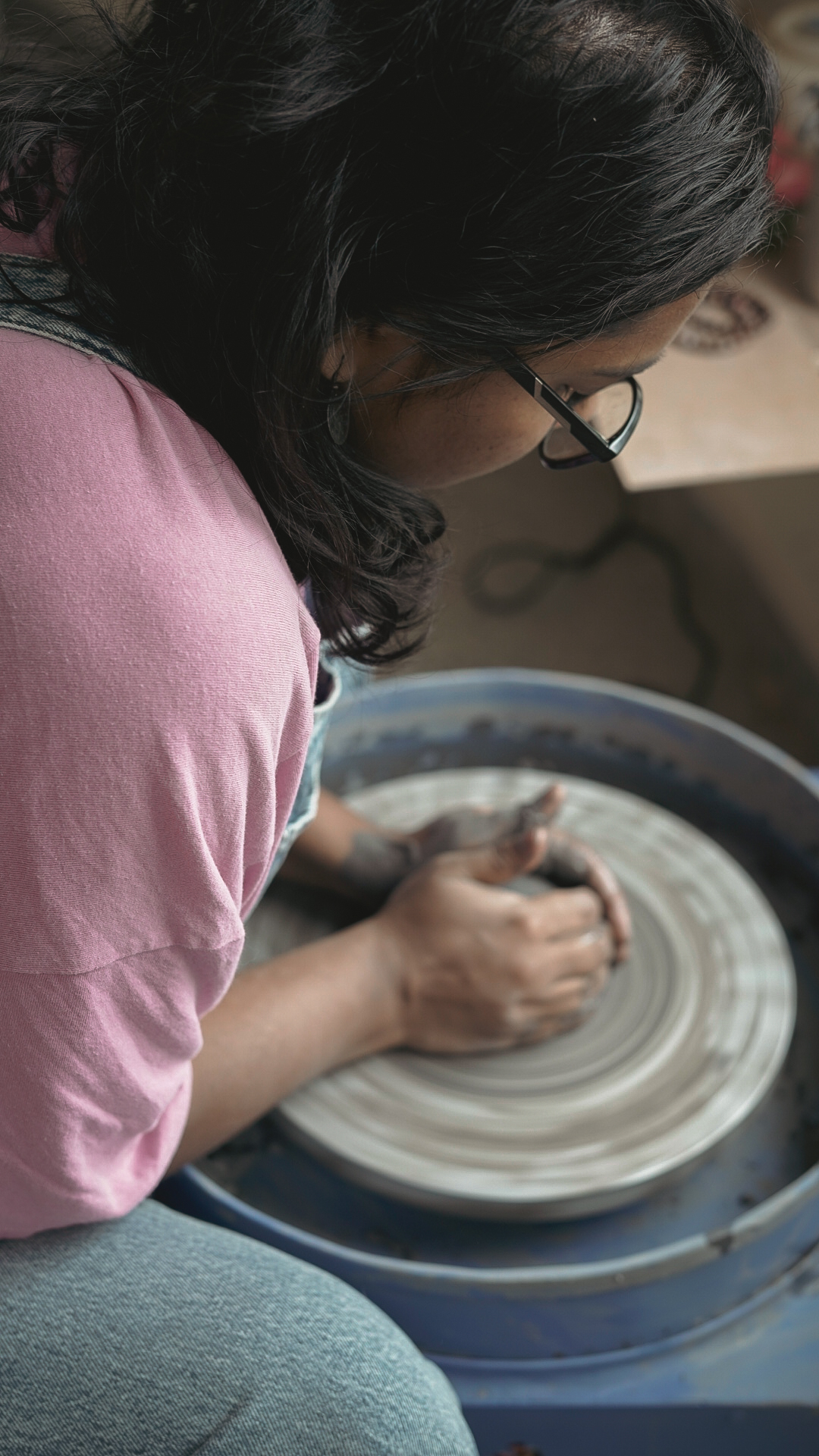 Over-shoulder view of a potter shaping clay
